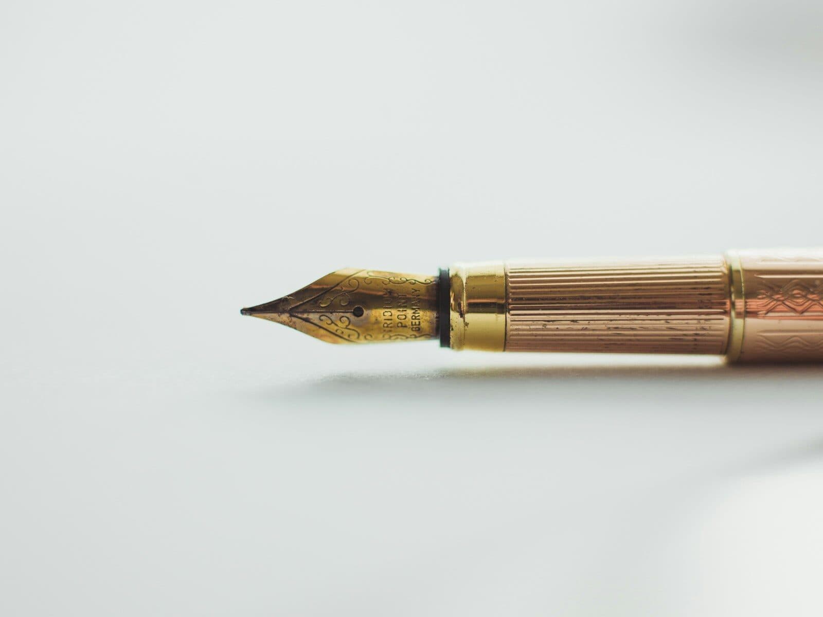 Pluma estilográfica dorada sobre una superficie clara