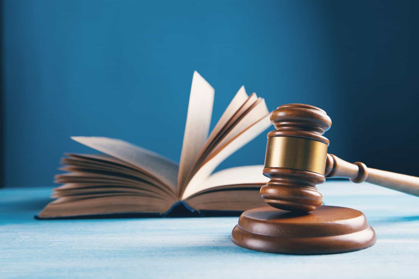 Mazo de juez junto a un libro abierto sobre una mesa azul, símbolo de la Constitución española